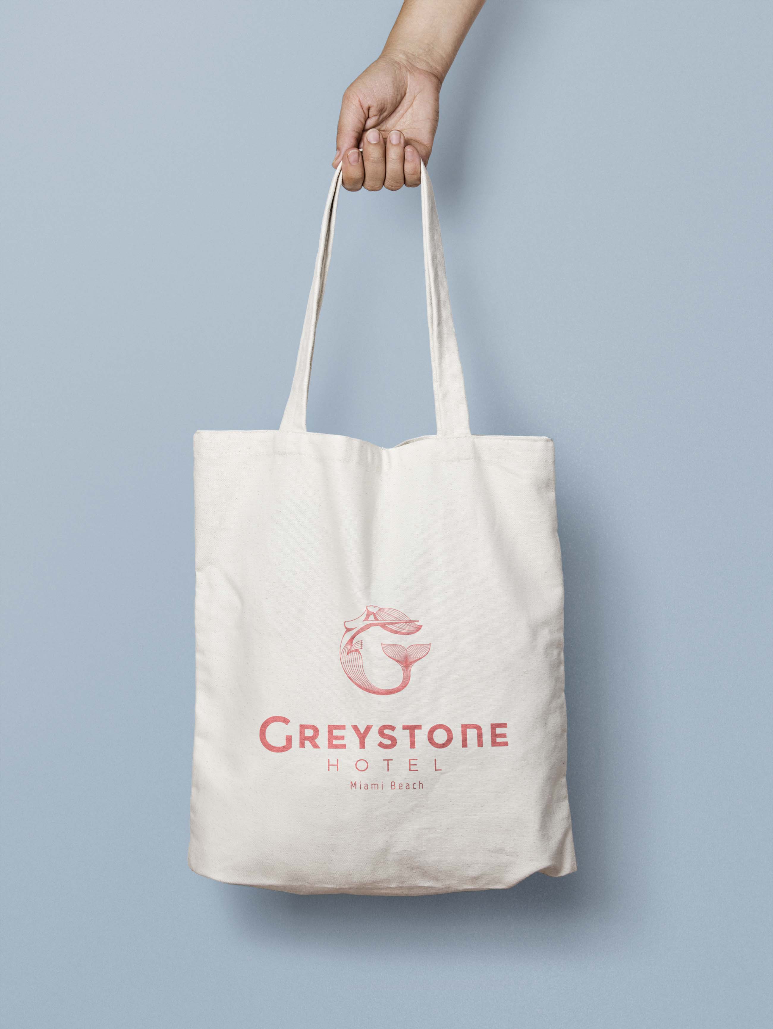 hand holding a white Canvas Tote bag branded with the Gresytone logo in pink color