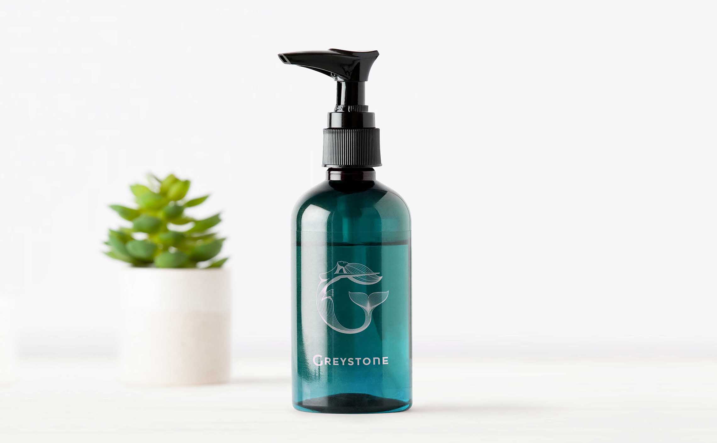 Blue hand sanitizer pump bottle branded with the Greystone logo