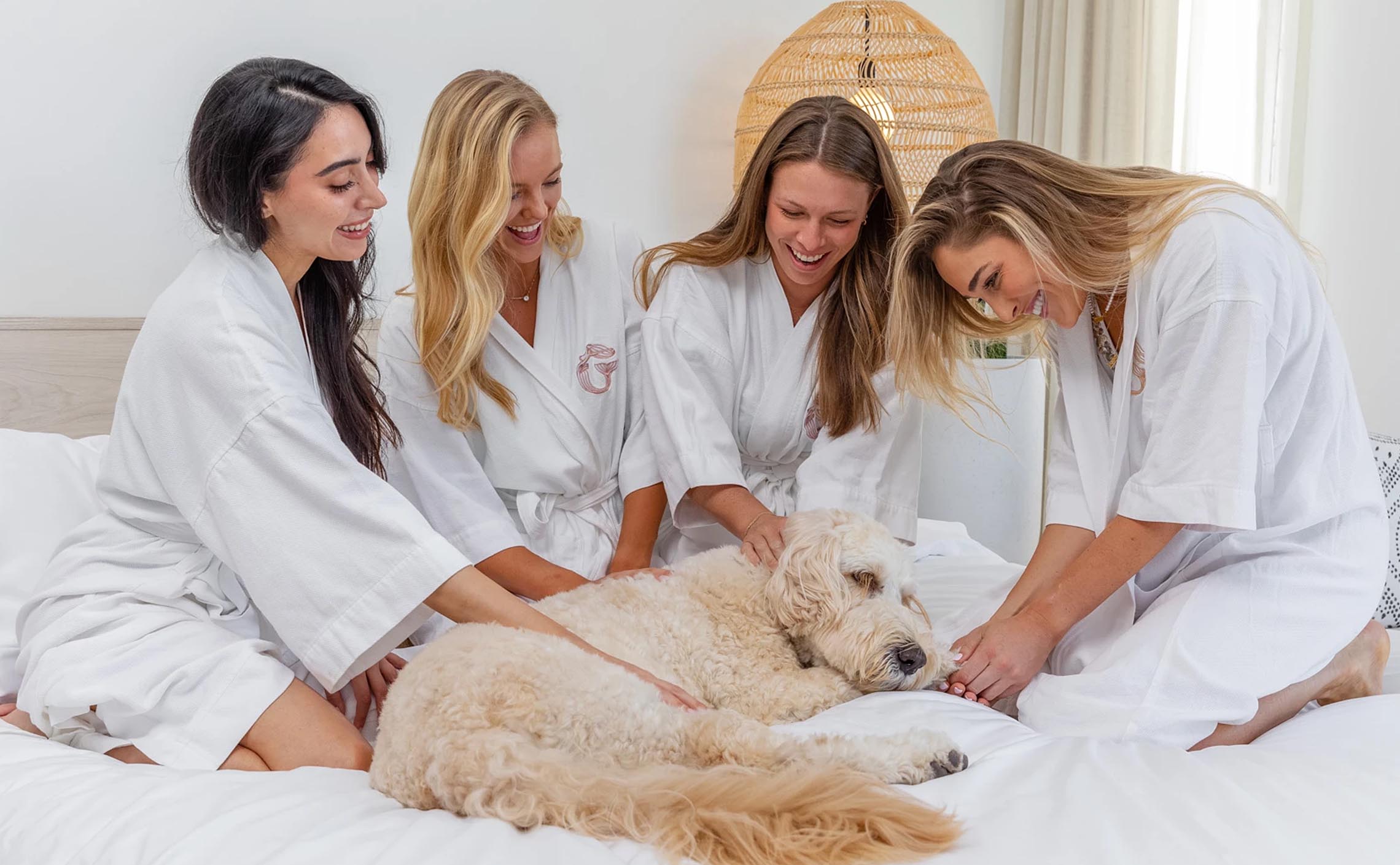 Girls in a white kimono with Mermaid logo embroidered sitting on a bed and petting a cute dog